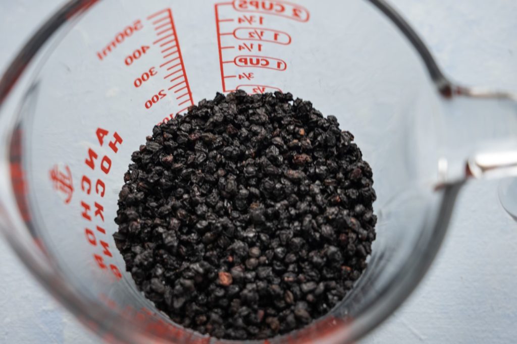 Dried Elderberry in a measuring cup, overhead shot