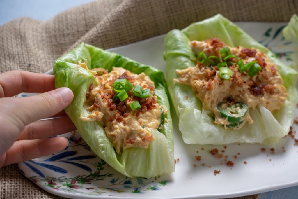 A hand grabbing lettuce wrapped in crack chicken